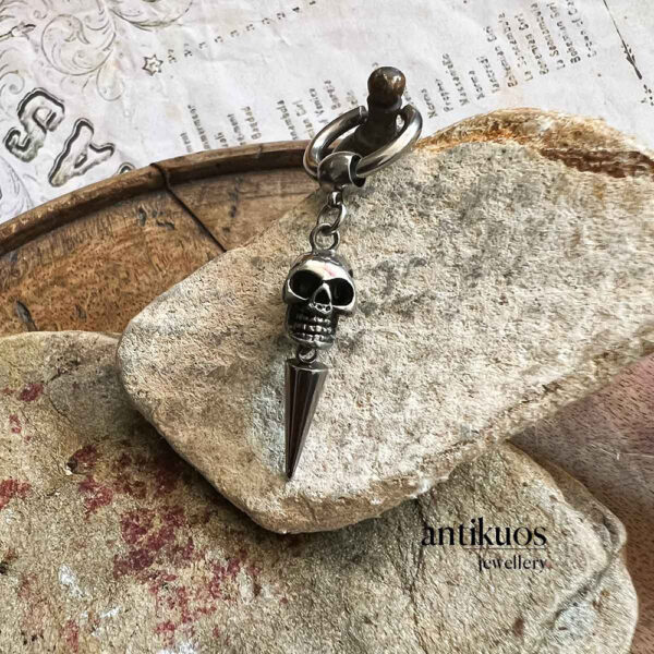 Skull and spike keychain jewellery on stone surface.